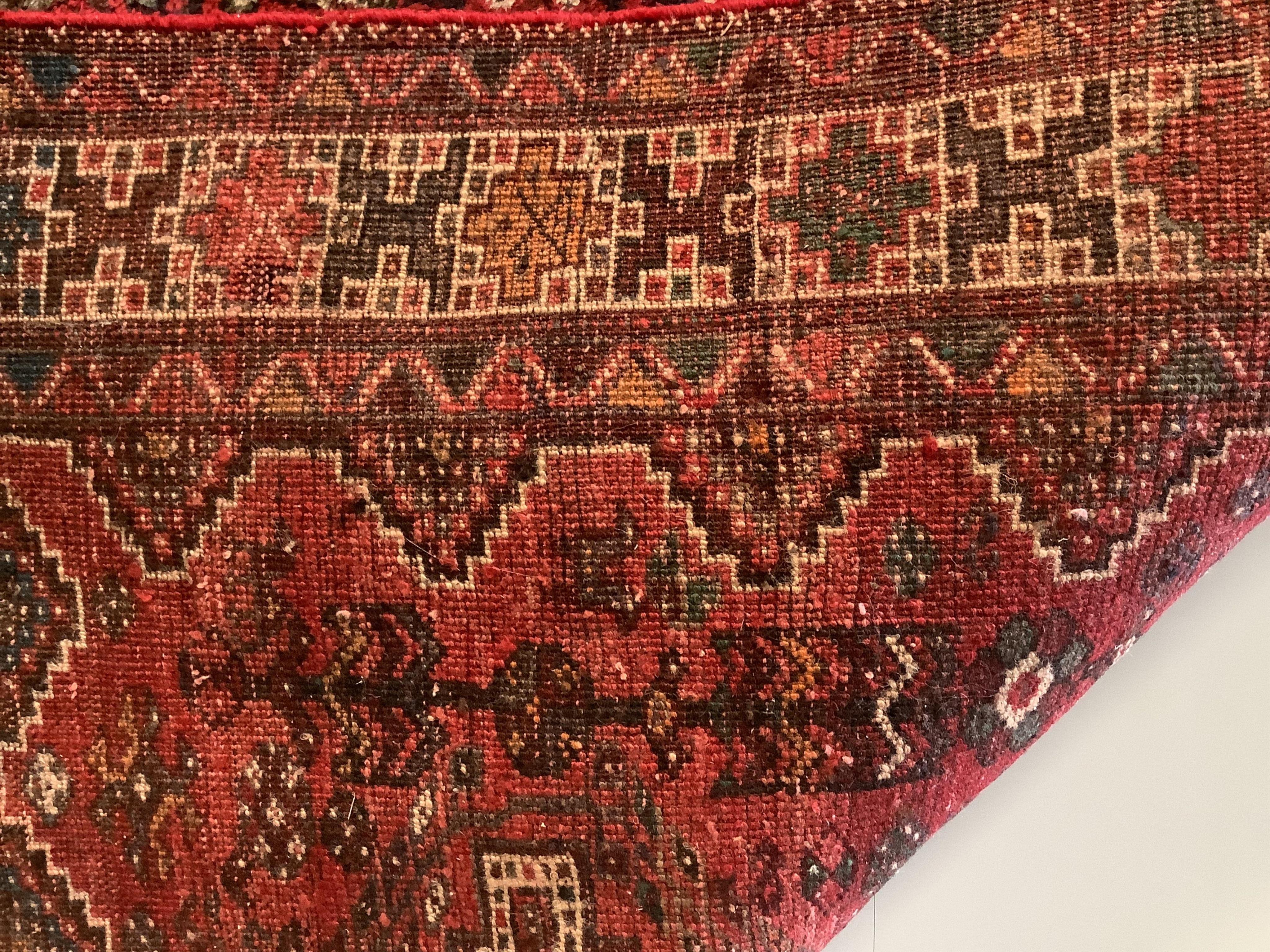 A Shiraz red ground rug, 200 x 157cm. Condition - fair